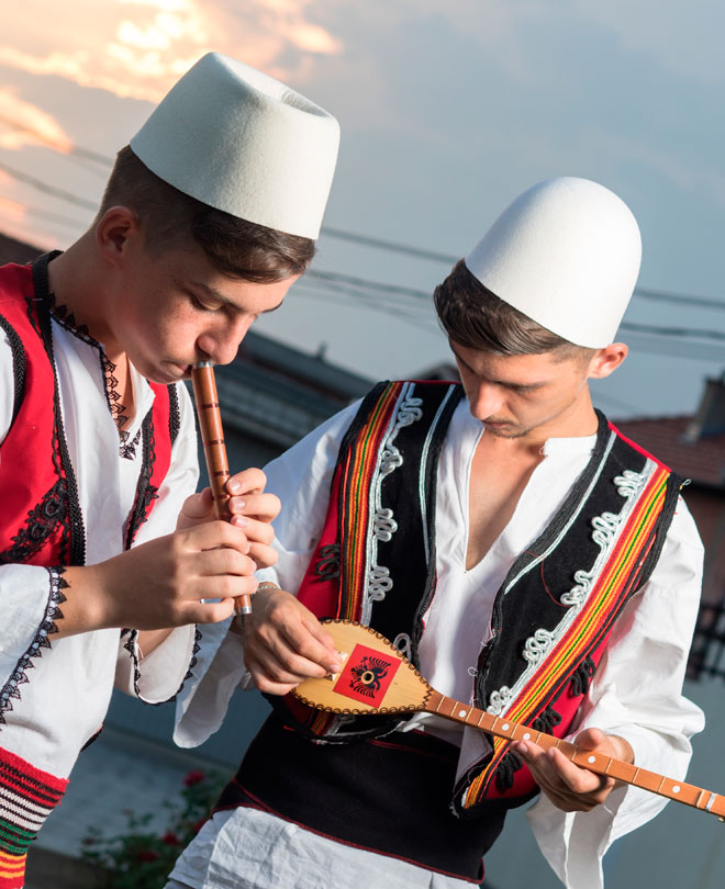 Albanska pojkar spelar musik i traditionell kostym